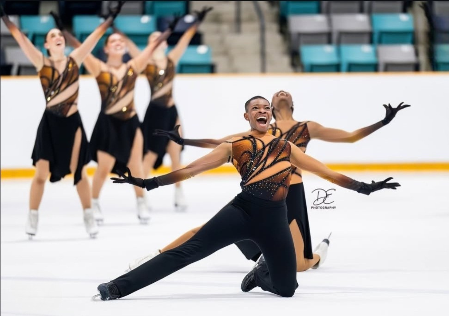 Synchro skaters in black and gold costumes by EliteXpression